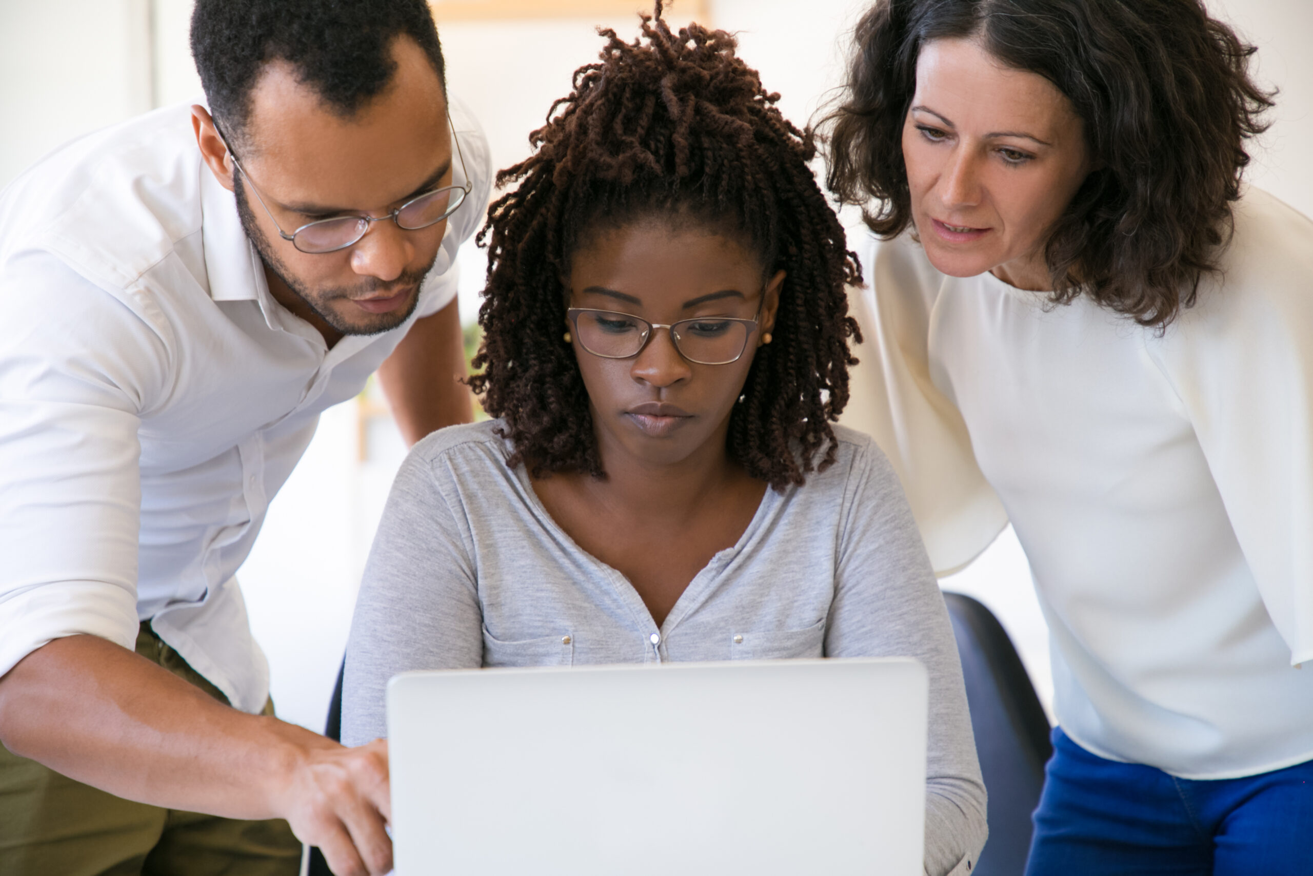 Team collaborating on a laptop while reviewing corporate software details.